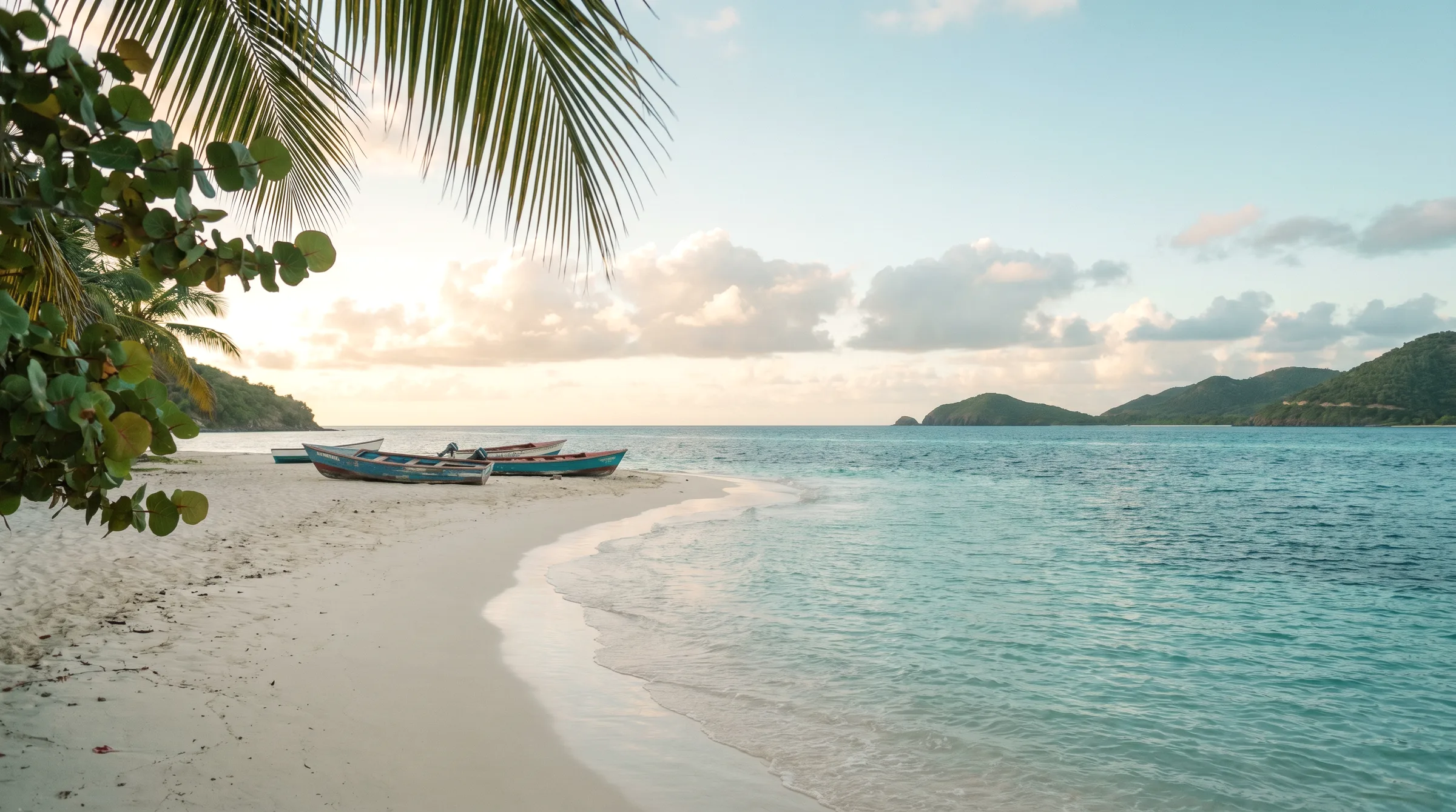 A Caribbean beach in soft afternoon light — sand, turquoise water, palm shadow.