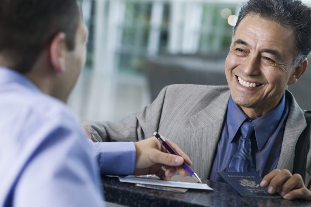 Businessman with Passport talking to a man across an airport counter - Citizenship by Investment - PassPro Banner image